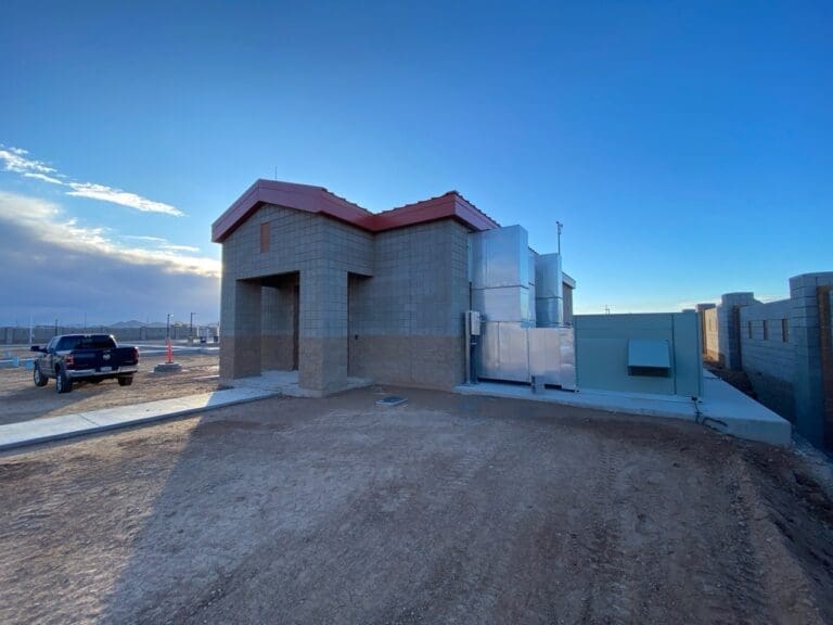 Lift Station exterior with a newly constructed building featuring HVAC systems and a truck parked nearby, under a clear blue sky