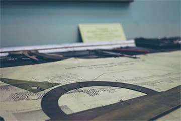 Architectural blueprints with drafting tools laid out on a planning table