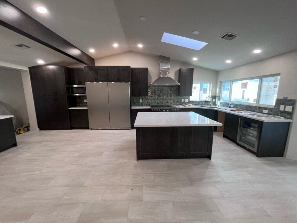 Modern Ahwatukee kitchen remodel featuring dark shaker cabinetry, quartz island, stainless steel appliances, skylight ceiling, upgraded tile flooring, and an open-concept layout with contemporary finishes.