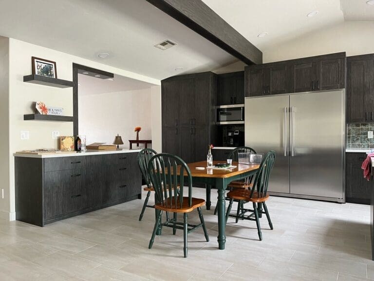 Completed Ahwatukee kitchen remodel featuring floor-to-ceiling custom cabinetry, integrated dining space, oversized stainless steel refrigerator, modern quartz countertops, floating accent shelves, and contemporary open-plan kitchen finishes with upgraded lighting and tile flooring.