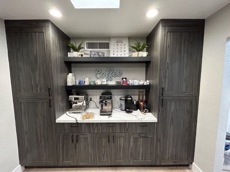 Built-in coffee station with dark wood cabinets, a marble countertop, and open shelves displaying mugs, coffee supplies, and small appliances including espresso and coffee machines.