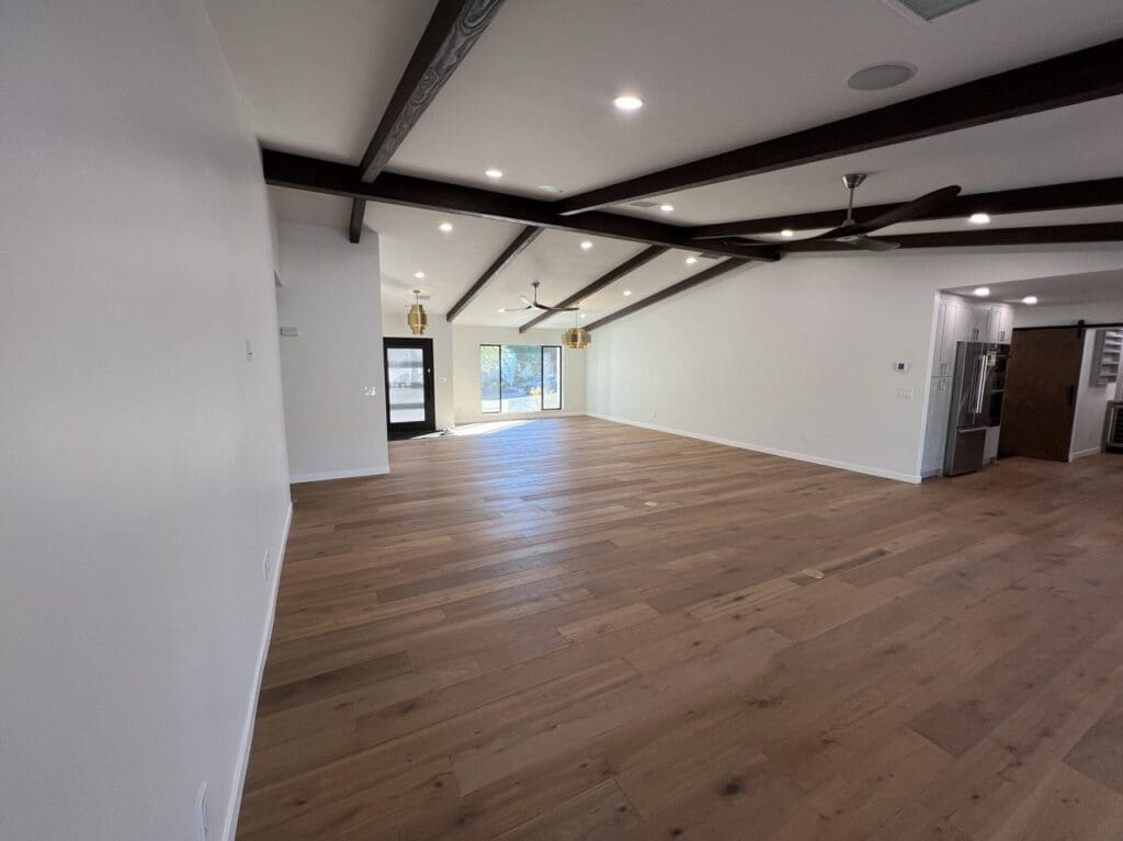 Wide open living area with wood floors, exposed beams, and ample natural light.