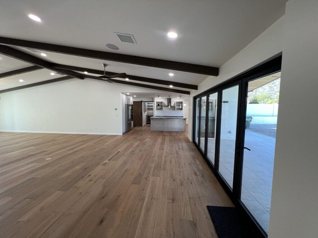 Open-concept living space with wood flooring, exposed beams, and sliding glass doors for seamless indoor–outdoor flow.
