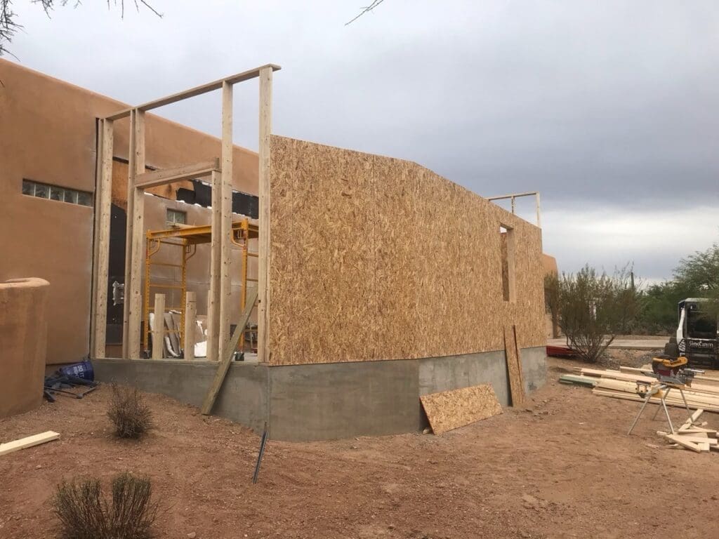Exterior view of North Scottsdale home addition with new wall framing and OSB sheathing installed over concrete foundation