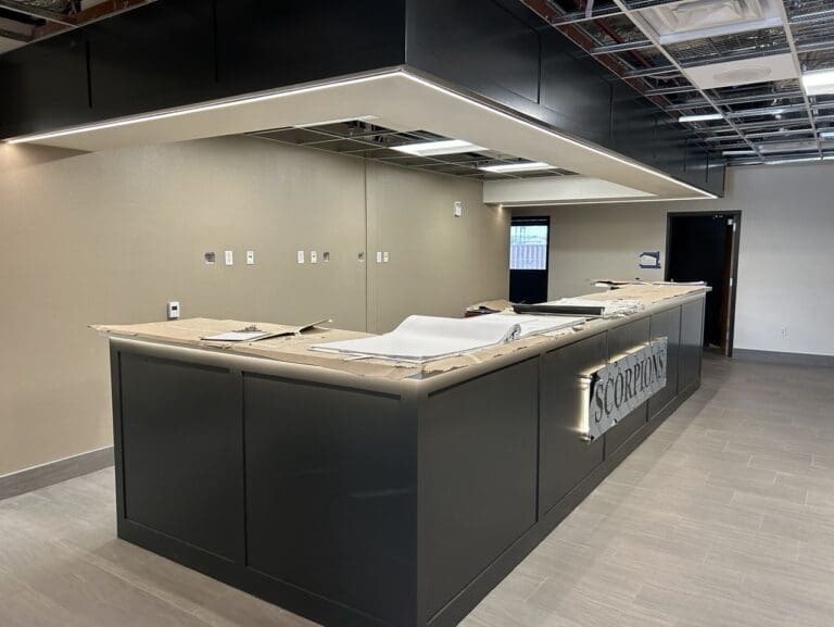 Office hangar renovation showing a newly installed front reception desk and unfinished ceiling work in progress