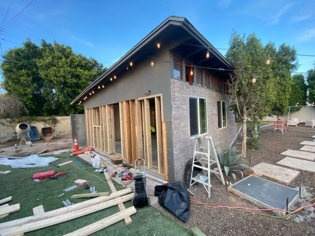 Phoenix garage-to-casita conversion in progress featuring exterior framing, modern sloped roofline, new window installations, backyard landscaping, and active construction transforming the detached garage into a contemporary living space.