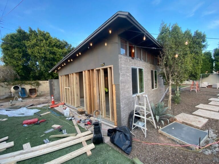 Phoenix garage-to-casita conversion in progress featuring exterior framing, modern sloped roofline, new window installations, backyard landscaping, and active construction transforming the detached garage into a contemporary living space.