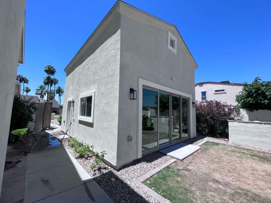 Modern detached casita exterior with smooth stucco finish, large sliding glass doors, minimalist landscaping, and contemporary backyard guest house design.