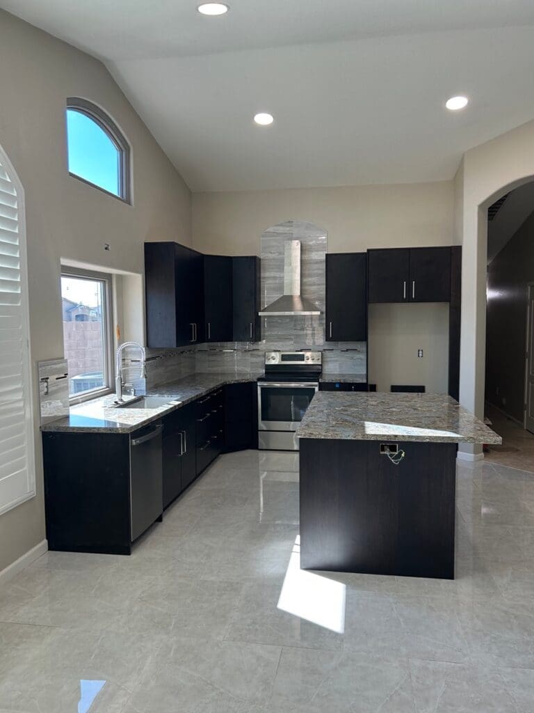 Phoenix kitchen remodel featuring vaulted ceilings, oversized granite island, dark espresso cabinetry, and modern open-concept kitchen with stainless steel finishes