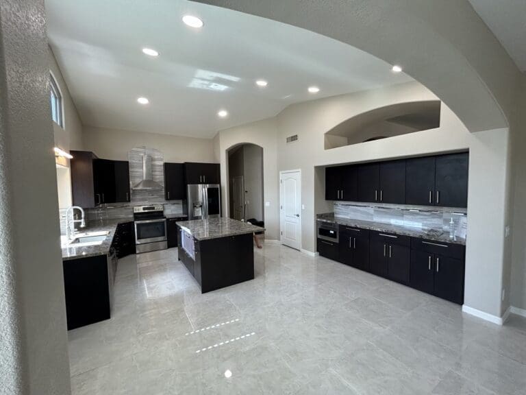 Phoenix kitchen remodel featuring expansive open-concept layout, oversized granite island, dark espresso cabinetry, recessed lighting, and luxury modern finishes