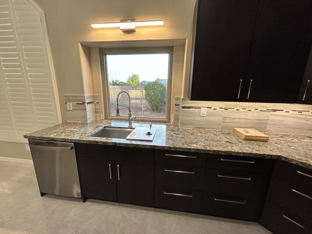 Phoenix kitchen remodel with dark espresso cabinetry, granite countertops, stainless steel sink, and modern under-window kitchen workspace design