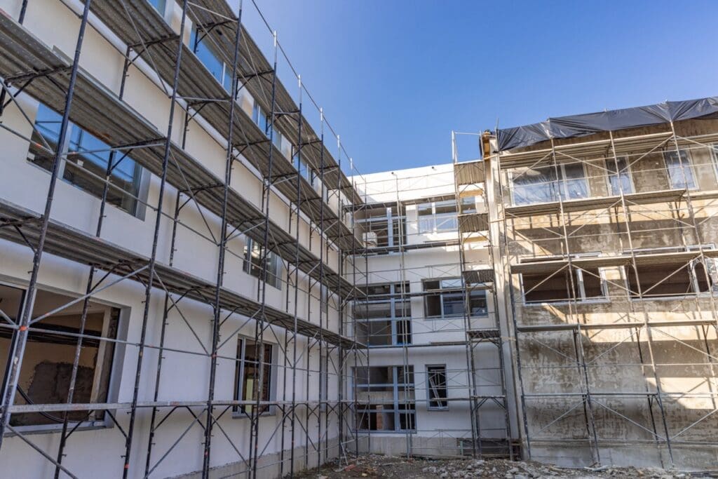 Multi-story building under renovation with scaffolding surrounding the exterior and unfinished walls visible