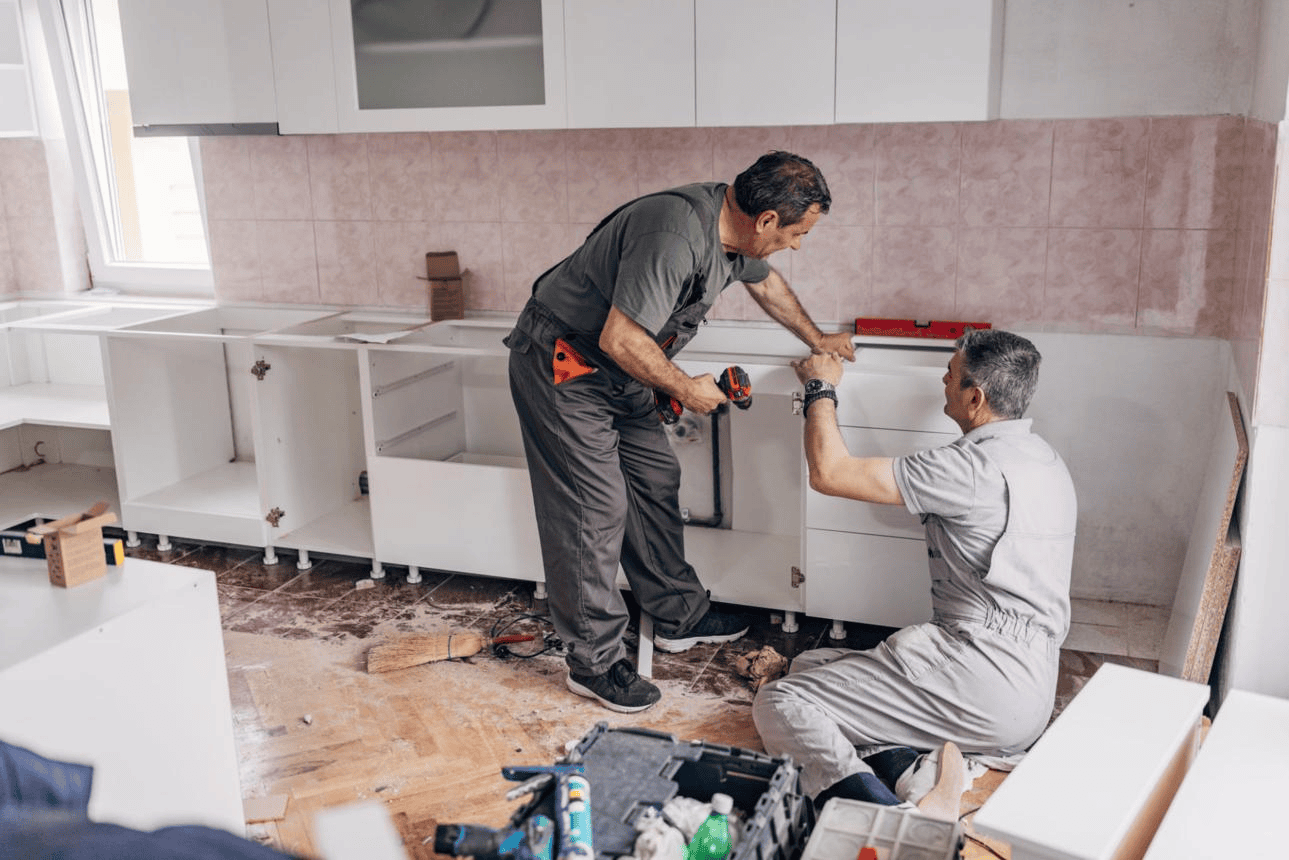 Two contractors installing lower kitchen cabinets during a remodel